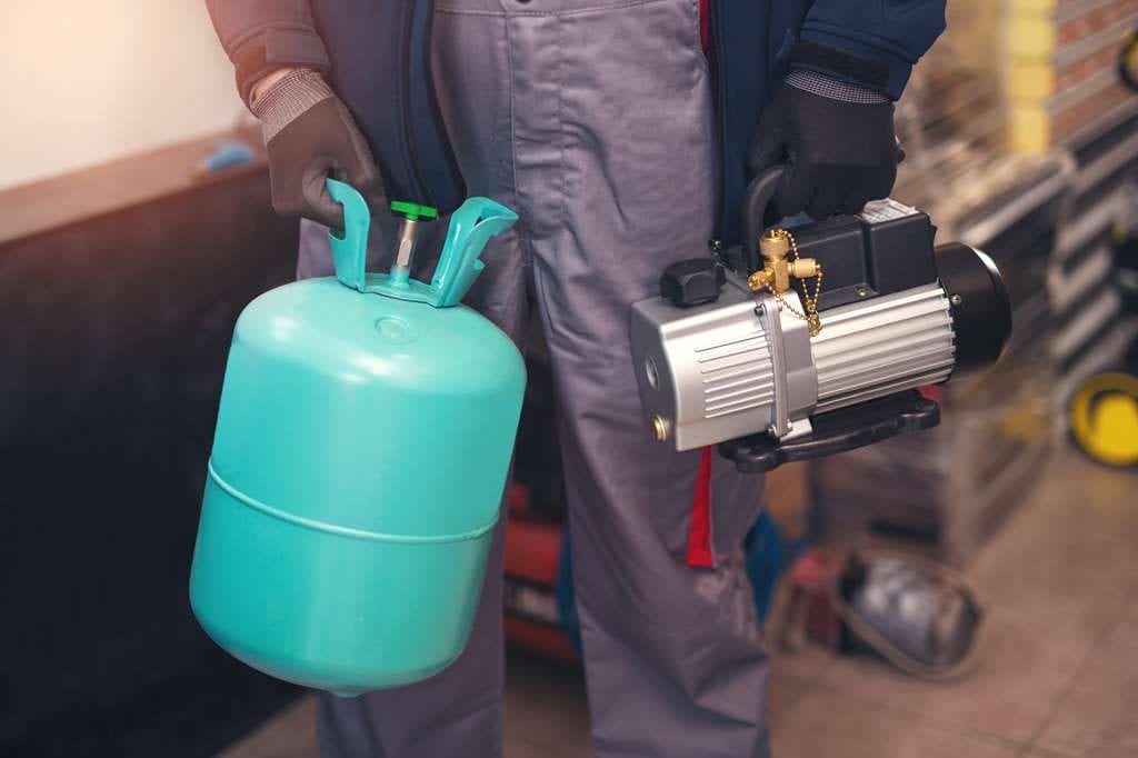 Technician with refrigerant and vacuum pump